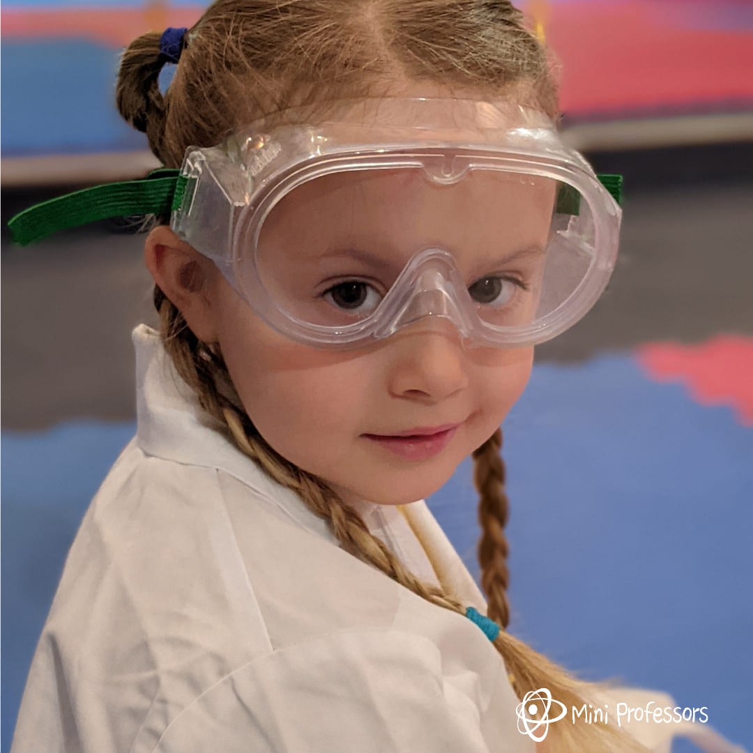A young scientist in a lab coat and safety goggles